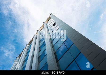 Vertikale Perspektive eines modernen Gebäudes mit reflektierenden Fenstern vor einem klaren blauen Himmel Stockfoto