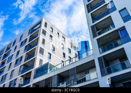 Modernes mehrstöckiges Wohngebäude mit lebhafter Fassade, großen Balkonen und malerischer Skyline unter klarem blauem Himmel Stockfoto