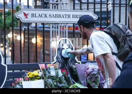 Broad Street, Birmingham, 22. Juli 2025: Fans von Ozzy Osbourne kommen zur Black Sabbath Bridge in Birmingham, um Ozzy Osbourne, der im Alter von 76 Jahren gestorben ist, ihre Anerkennung zu zollen. Blumen, Karten und Kerzen wurden auf der Bank gelassen und einige Leute tranken und teilten sie mit dem Bild von Ozzy auf der Bank. Quelle: British News und Media/Alamy Live News Stockfoto