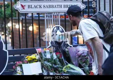 Broad Street, Birmingham, 22. Juli 2025: Fans von Ozzy Osbourne kommen zur Black Sabbath Bridge in Birmingham, um Ozzy Osbourne, der im Alter von 76 Jahren gestorben ist, ihre Anerkennung zu zollen. Blumen, Karten und Kerzen wurden auf der Bank gelassen und einige Leute tranken und teilten sie mit dem Bild von Ozzy auf der Bank. Quelle: British News und Media/Alamy Live News Stockfoto