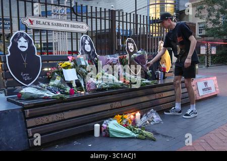 Broad Street, Birmingham, 22. Juli 2025: Fans von Ozzy Osbourne kommen zur Black Sabbath Bridge in Birmingham, um Ozzy Osbourne, der im Alter von 76 Jahren gestorben ist, ihre Anerkennung zu zollen. Blumen, Karten und Kerzen wurden auf der Bank gelassen und einige Leute tranken und teilten sie mit dem Bild von Ozzy auf der Bank. Quelle: British News und Media/Alamy Live News Stockfoto