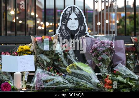 Broad Street, Birmingham, 22. Juli 2025: Fans von Ozzy Osbourne kommen zur Black Sabbath Bridge in Birmingham, um Ozzy Osbourne, der im Alter von 76 Jahren gestorben ist, ihre Anerkennung zu zollen. Blumen, Karten und Kerzen wurden auf der Bank gelassen und einige Leute tranken und teilten sie mit dem Bild von Ozzy auf der Bank. Quelle: British News und Media/Alamy Live News Stockfoto