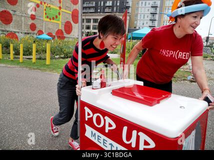 24. September 2016 - St. Paul, St. Paul, USA - Pop Up Meeting Truck, das zweijährige Programm und die Idee der City-Künstlerin Amanda Lovelee, wird bei seiner letzten Veranstaltung -- die Year-End-Party für Urban Flower Field im Pedro Park Samstag, 24. September 2016, in St. Paul, MN, stattfinden. Pop-up-Meeting bringt das öffentliche Meeting zur Öffentlichkeit und verschenkt Eis als Belohnung für die Teilnahme.hier bekommt Lovelee, links, eine Hand, die den Pop-up-Eiswagen von Colleen Sheehy, President und Executive Director von Public Art Saint Paul, drückt. Pop Up Meeting Truck und Mitarbeiter werden bei der Year End Party für die Urba sein Stockfoto