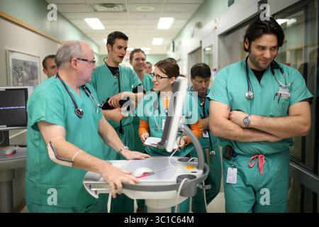 NEAPOLIS - 11/17/09 - das Hennepin County Medical Center, das mehr arme Menschen als jedes andere Krankenhaus im Bundesstaat versorgt, aber auch renommierte Ausbildungs- und Spezialdienstleistungen betreibt, liegt im Herzen der Gesundheitskosten des Bundesstaates. AUF DIESEM FOTO: Die Bewohner der HCMC-Notaufnahme und Ärzte gingen einen Flur entlang, als sie von der Seniorin Chad Roline, zweiter von links, über die Patienten informiert wurden, die sie betreuen würden, als die Nachtschicht am Dienstag begann. Auf der linken Seite war Dr. Dave Plummer. Sarah Bronner sprach mit Plummer und machte sich Notizen auf einem Klemmbrett. Name des Wohnsitzes rechts Stockfoto