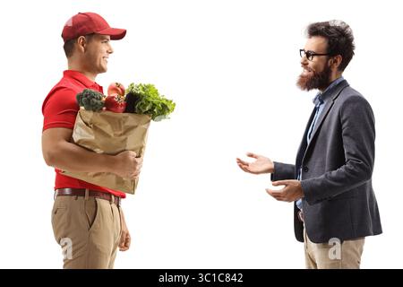 Profilaufnahme eines Lieferers, der einem bärtigen Mann eine Einkaufstasche liefert, isoliert auf weißem Hintergrund Stockfoto