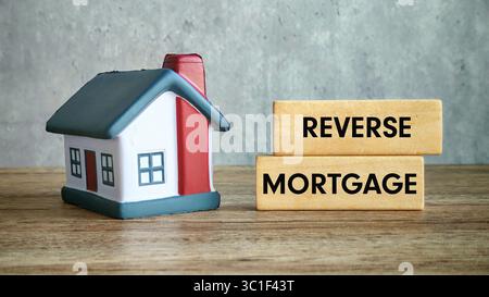 Reverse Hypotheken-Konzept mit Miniaturhaus und Holzblöcken auf einem Tisch Stockfoto