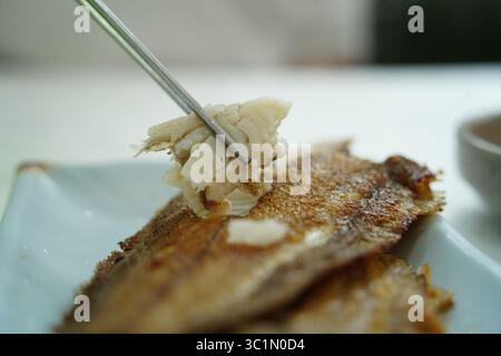 Nahaufnahme von frittiertem Fischfilet, das mit Essstäbchen aufgefangen wird Stockfoto