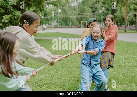 Multiethnische Kinder spielen Tug of war in Park Stockfoto