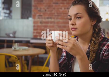 Frau mit Keramikbecher und Blick direkt auf den Holztisch des Cafés mit gelben Stühlen, Kopierraum Stockfoto