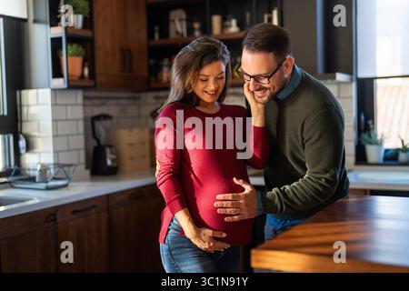 Zärtlicher Moment, der Ehemann umarmt liebevoll den Bauch seiner schwangeren Frau, während sie Zeit miteinander verbringen Stockfoto