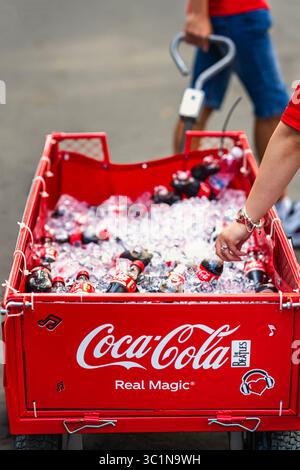 Roter Wagen gefüllt mit Eis und Coca-Cola-Flaschen werden während der Veranstaltung im Freien angeboten. Konzept von Coca-Cola als Symbol für echte Magie, Erfrischung, Teil davon Stockfoto