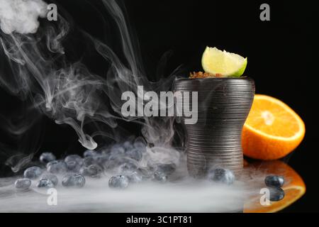 Shisha Schüssel mit Rauch und Früchten auf schwarzem Tisch, Nahaufnahme Stockfoto