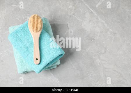 Stapel weicher Handtücher und Bürsten auf grauem Marmortisch, Blick von oben. Leerzeichen für Text Stockfoto