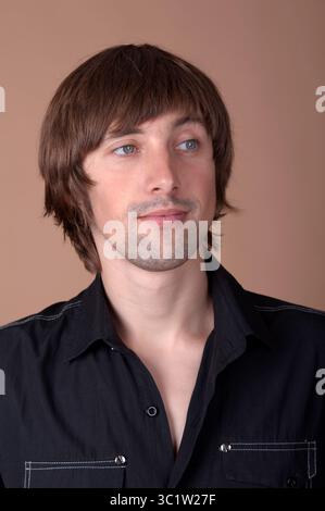 Ein junger Mann mit stilvollen Haaren steht selbstbewusst und fesselt den Zuschauer. Stockfoto