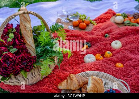 Ein lebhaftes Picknick im Herbst bietet farbenfrohe saisonale Speisen – helle Kürbisse, Äpfel, Wurstwaren, frisches Brot, Käse, und warme Getränke. Umschlossen b Stockfoto