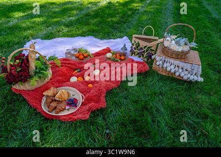 Ein lebhaftes Picknick im Herbst bietet farbenfrohe saisonale Speisen – helle Kürbisse, Äpfel, Wurstwaren, frisches Brot, Käse, und warme Getränke. Umschlossen b Stockfoto