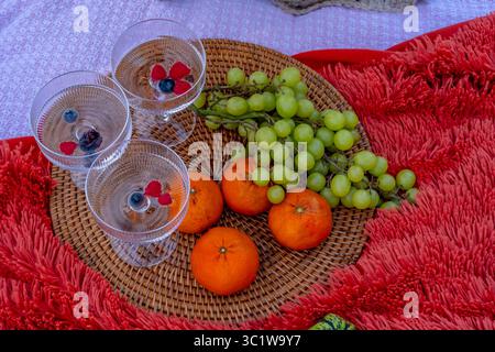 Ein lebhaftes Picknick im Herbst bietet farbenfrohe saisonale Speisen – helle Kürbisse, Äpfel, Wurstwaren, frisches Brot, Käse, und warme Getränke. Umschlossen b Stockfoto