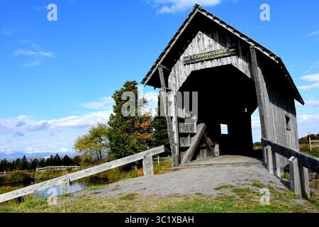 Die verwitterte und verblasste A. M. Foster Covered Bridge besteht aus Holz und hat ein einzelnes Fenster auf jeder Seite. Die Brücke überspannt einen kleinen Teich in der Nähe von Cabot, Ver Stockfoto