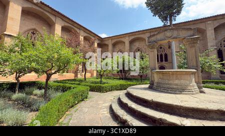 Besucher genießen die ruhige Atmosphäre in der Catedral de Siguenza, umgeben von gepflegten Gärten und einem dekorativen Brunnen. Die Architektur zeigt Stockfoto