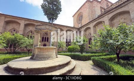 Besucher genießen den ruhigen Innenhof der Catedral de Siguenza in Spanien, der eine komplexe Steinarchitektur, einen zentralen Brunnen und das lebhafte greene bietet Stockfoto