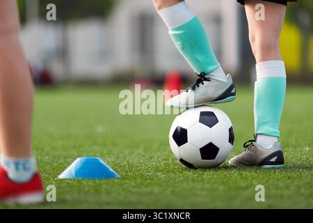 Eine Nahaufnahme eines jungen Fußballspielers in Fußballsocken und Stollen mit schwarz-weißem Fußball auf einem grünen Rasenfeld. Fußballer im Training Stockfoto