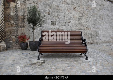Ein Park mit einer Holzbank vor einer Festungsmauer. Stockfoto