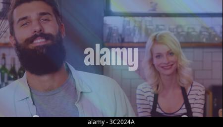 Lächelnde Baristas in Schürze hinter einer Holzbar mit Glaswaren und Flaschen im Fenster Stockfoto