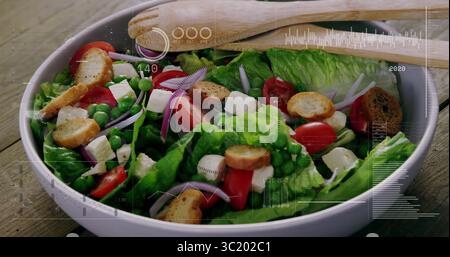 Mit weißer Keramikschale mit frischem Salat und Holzlöffeln auf Holztisch mit Überlagerung Stockfoto