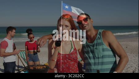 Trinken Bier unter chilenischer Flagge am Strand, rothaarige Frau im Sommerkleid und Mann mit dunklen Flaschen Stockfoto