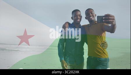 Lächelnde Freunde machen Selfie an der Sandküste mit Dschibuti-Flaggenüberzug, mit Smartphone Stockfoto