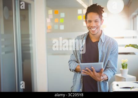 Afroamerikaner, der kariertes Hemd im Büro trägt, Tablette in der Nähe von Haftnotizen hält, Kopierraum Stockfoto