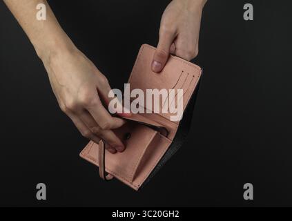 Weibliche Hände öffnen rosa Ledertasche auf schwarzem Hintergrund Stockfoto
