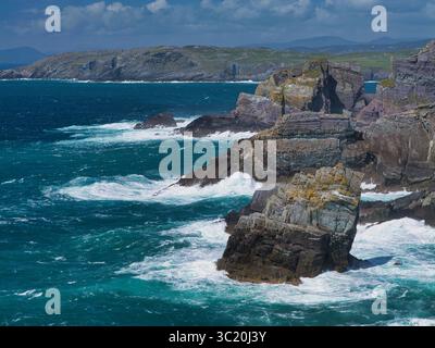 Atemberaubende Aussicht auf zerklüftete Klippen vor dem abstürzenden Atlantischen Ozean in Mizen Head, Irland, mit natürlicher Schönheit und Kraft. Stockfoto
