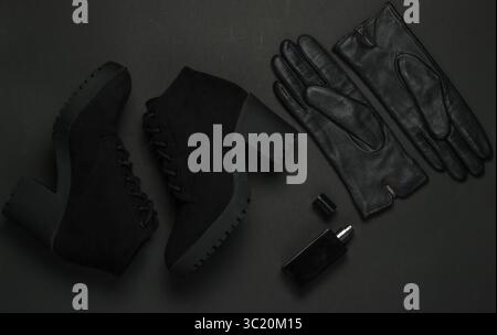 Modische Accessoires für Damen auf schwarzem Hintergrund. Wildlederstiefel, Lederhandschuhe, Parfümflasche. Draufsicht Stockfoto