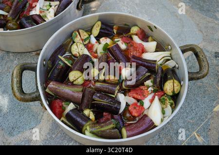 Traditionelle griechische „melitzanes giaxni“, zubereitet mit rohem Gemüse in zwei runden Metallschalen, von oben betrachtet. Stockfoto