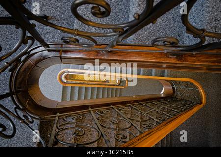 Dekorative Wendeltreppe mit schmiedeeisernem Geländer in einem historischen Gebäude, Blick von oben nach unten. Stockfoto