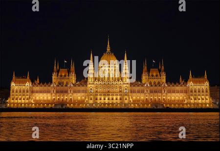 Bei Nacht die beleuchtete Fassade des ungarischen Parlamentsgebäudes, Budapest, Ungarn, auch bekannt als das Parlament von Budapest, mit Reflexionen auf die Donau Stockfoto