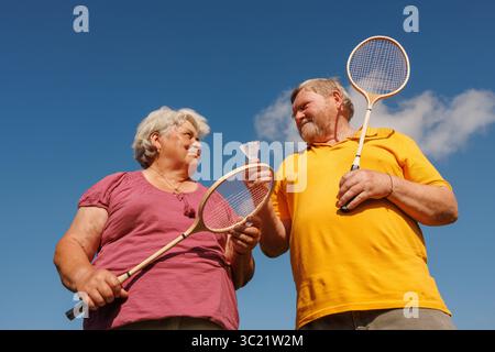 Glückliches Seniorenpaar, das gemeinsam Badminton und Outdoor-Aktivitäten genießt, fördert Wellness und aktives Altern Stockfoto