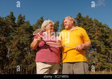 Glückliches Seniorenpaar, das Badminton im Park spielt, gesunde Erholung und aktiven Outdoor-Lifestyle im Ruhestand genießt Stockfoto