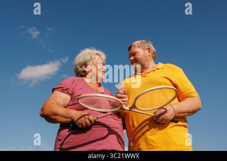 Fröhliches Seniorenpaar, das im Freien Badminton spielt, fördert Wellness, Freundschaft und einen aktiven Lebensstil im Ruhestand Stockfoto