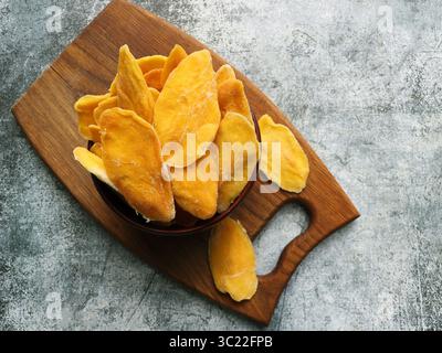 Getrocknete Mangobänder in Holzschale. In Scheiben geschnittene, dehydrierte Mangos. Stockfoto