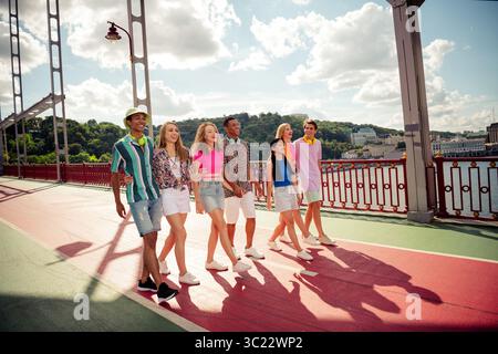 Junge Freunde, die einen Sommertag auf einer sonnigen Stadtbrücke genießen und bei einem zwanglosen Ausflug Zweisamkeit und Freude zeigen Stockfoto
