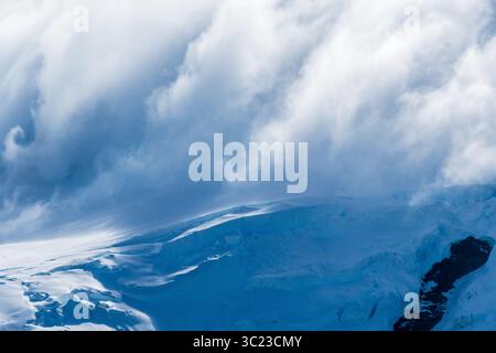 Eine beschauliche antarktische Landschaft in der Nähe des Hafens Mikkelsen auf Trinity Island, mit starken Reflexen, zerklüfteten Bergen und beeindruckenden Eisbergen Stockfoto