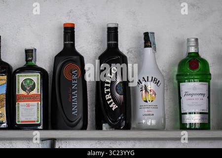 Cremona, Italien 19. Juli 2025 Spirituosenflaschen mit Jagermeister, Anima Nera, Mirtillo, Malibu, und Tanqueray, ordentlich auf einem Regal angeordnet Stockfoto