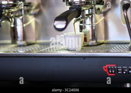 Cremona, Italien - 19. Juli 2025 Nahaufnahme eines Espresso, der aus einer professionellen Kaffeemaschine in eine weiße Tasse in einem Café gebrüht wird Stockfoto