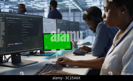 Systemadministrator verwendet Tablets mit isoliertem Bildschirm, die in der Serverfarm arbeiten, um sie für Datenverarbeitungsanforderungen zu optimieren. Software-Entwickler kodieren auf Chroma-Schlüsselgerät im Rechenzentrum, Kamera A Stockfoto