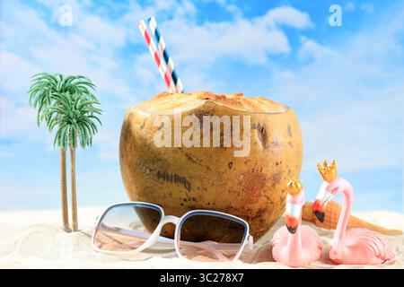 Eine Szene am Meer, Kokosgetränke mit Papierstroh auf Sand, junge Kokosnuss mit Miniatur-on-Beach-Konzept. Erfrischungsgetränk Im Sommer Stockfoto