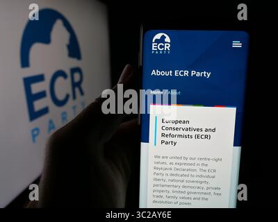 In dieser Abbildung hält eine Person ein Handy mit der Webseite der Konservativen und Reformisten (EKR) auf dem Bildschirm vor dem Logo. Stockfoto