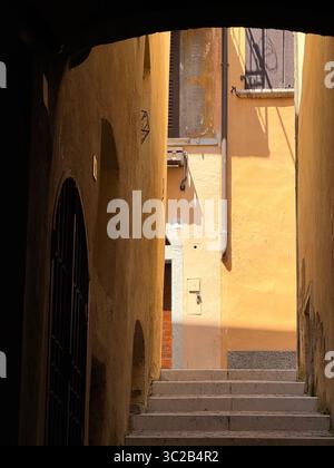 Abstrakt von gelben Wänden, die von der Sonne beleuchtet werden, in einem Durchgang in Salo, Italien Stockfoto