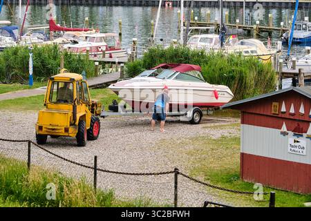 6. Juli 2025 – Lauterbach-Deutschland: Ein Mann schickt ein Schnellboot mit einem kompakten Radlader mit Gabeln und Kraftheber in den Hafen, vor dem Ankerplatz Stockfoto